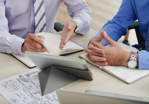 Close-up image of coworkers discussing data on tablet computer screen